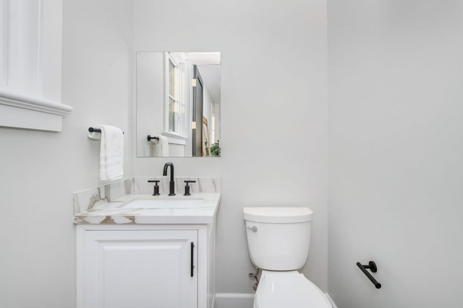 A White Color Themed Bathroom With Black Fittings